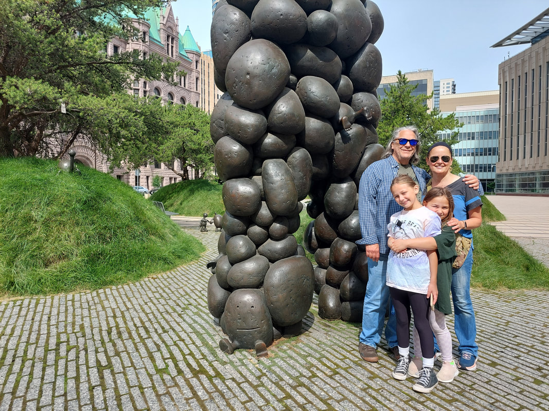 Family of four standing outside in front of sculpture in minneapolis
